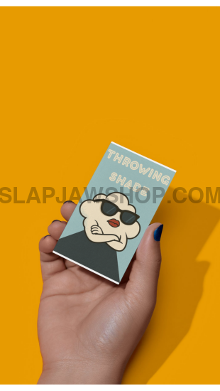 Hand holding a small book with a cover featuring a stylized face on an orange background