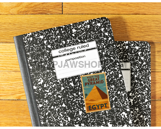 Two composition notebooks with a small book on top, all on a wooden surface.