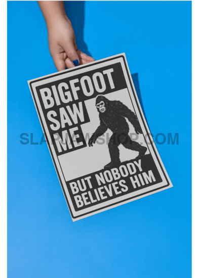 Laptop with a Bigfoot sticker on a table with a coffee cup, autumn foliage outside.