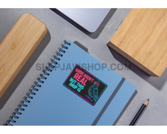 Blue notebook with a sticker on a gray surface with wooden blocks and a pencil.