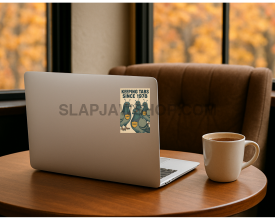Laptop with a sticker on a wooden table in front of a window with autumn foliage.