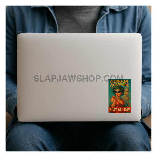 Person holding a laptop with a Gorgon Comics book cover sticker on a white background