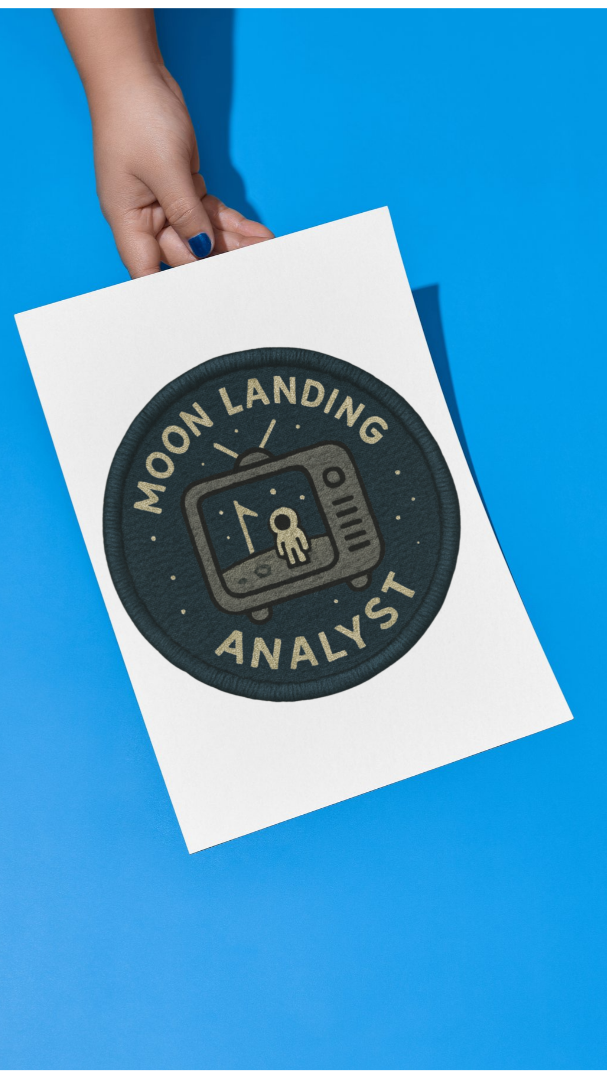 Hand holding a white paper with 'Moon Landing Analyst' text on a blue background