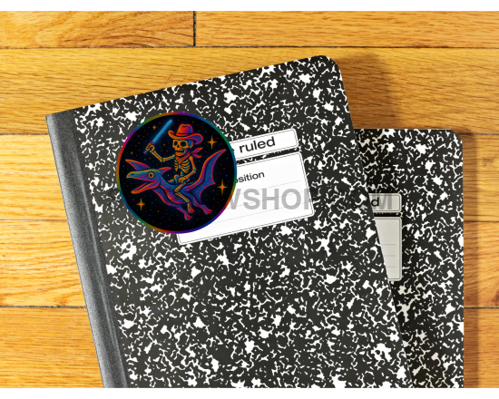 Two black and white notebooks on a wooden surface with a colorful sticker on one of them.