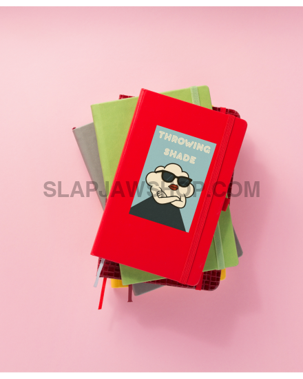 Stack of books with a red one on top featuring a face wearing sunglasses, on a pink background