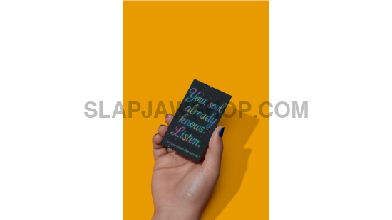 Hand holding a small book with text on a mustard yellow background